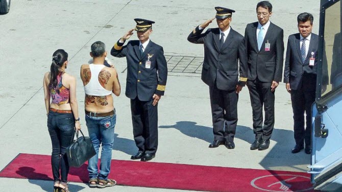 тайский наследный принц-плейбой прилетел в Германию, выйдя на торжественную встречу с женой и пуделем с татуировками на всю спину, прикрытую майкой-топом, напоминающим женскую