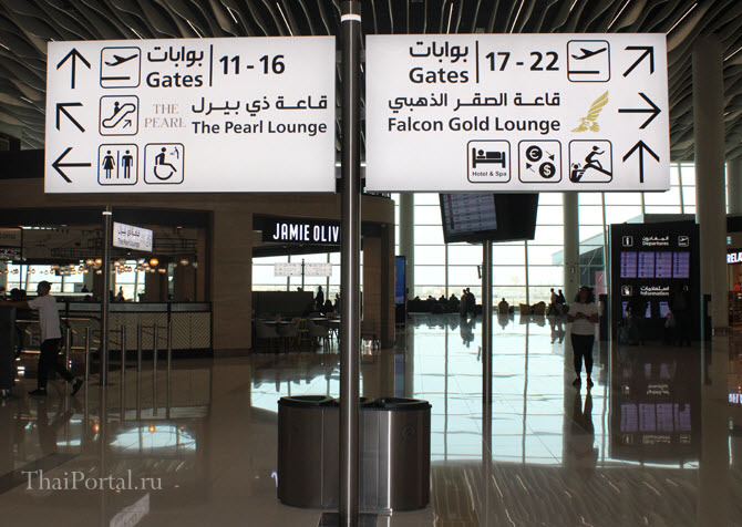 указатели с направлениями на бизнес-залы в аэропорту Бахрейна по разные стороны от центра здания в зоне вылета