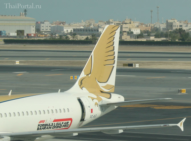 хвост и крыло самолета авиакомпании Gulf Air, стоящего возле гейта аэропорта Бахрейна (Манама)